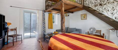 Een kamer met een bed, een tafel, een stoel, een trap en uitzicht op het buiten.