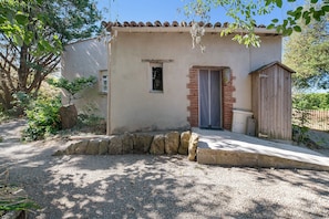 A small building with a tiled roof, a door, and a window.