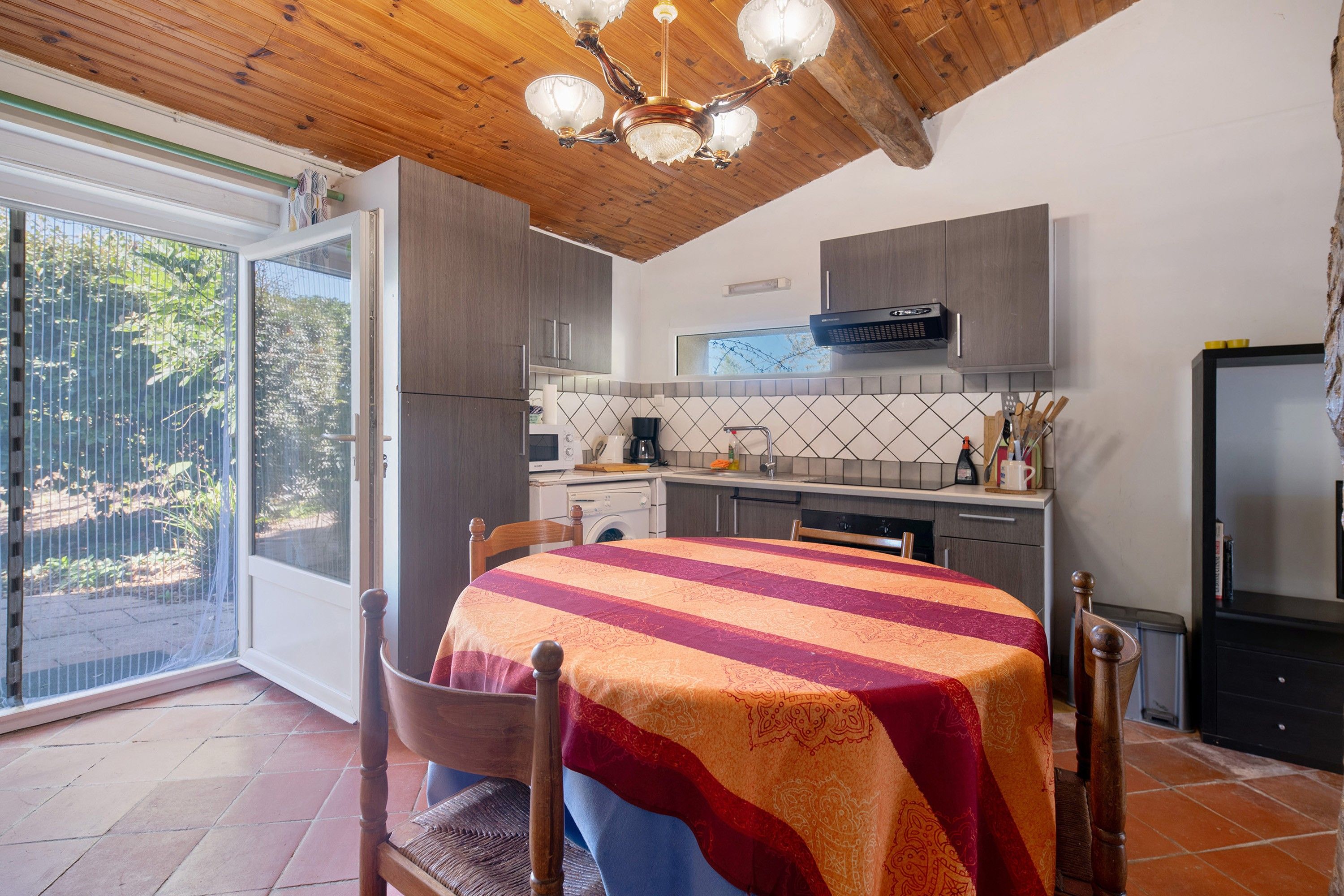 A kitchen with a dining area, a washing machine, and a large window.