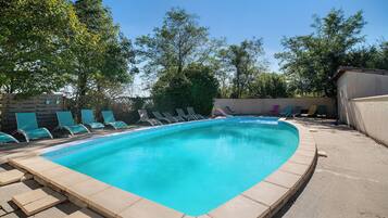 A rectangular swimming pool with a tiled edge, surrounded by a concrete deck.