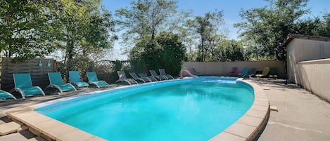 A rectangular swimming pool with a tiled edge, surrounded by a concrete deck.