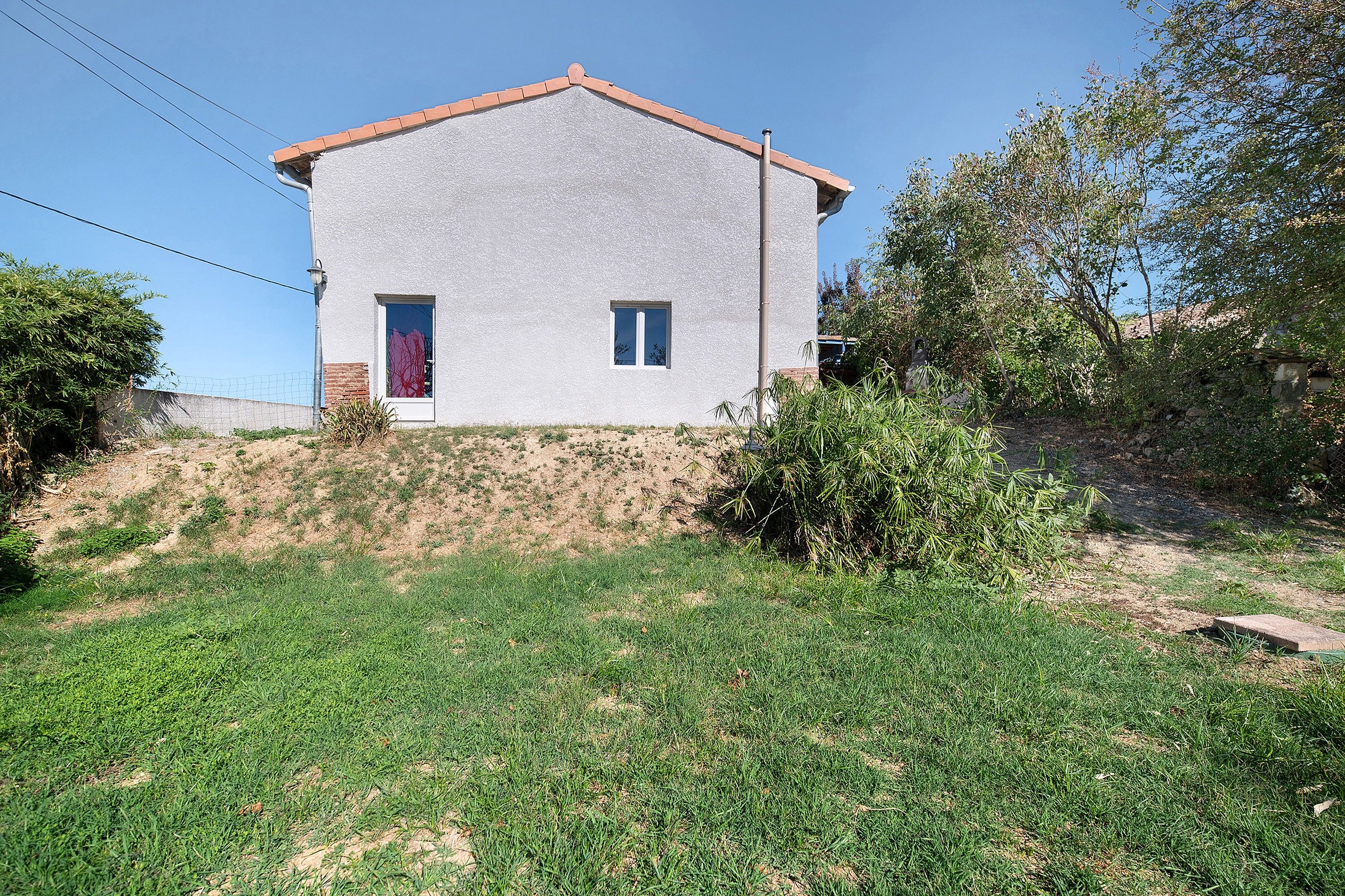 A single-story house with a flat roof, a small front yard, and a clear sky.