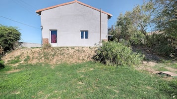 A single-story house with a flat roof, a small front yard, and a clear sky.