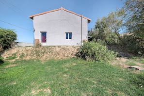 Eingeschossiges Haus mit flachem Dach, einem kleinen Vorgarten und blauem Himmel.