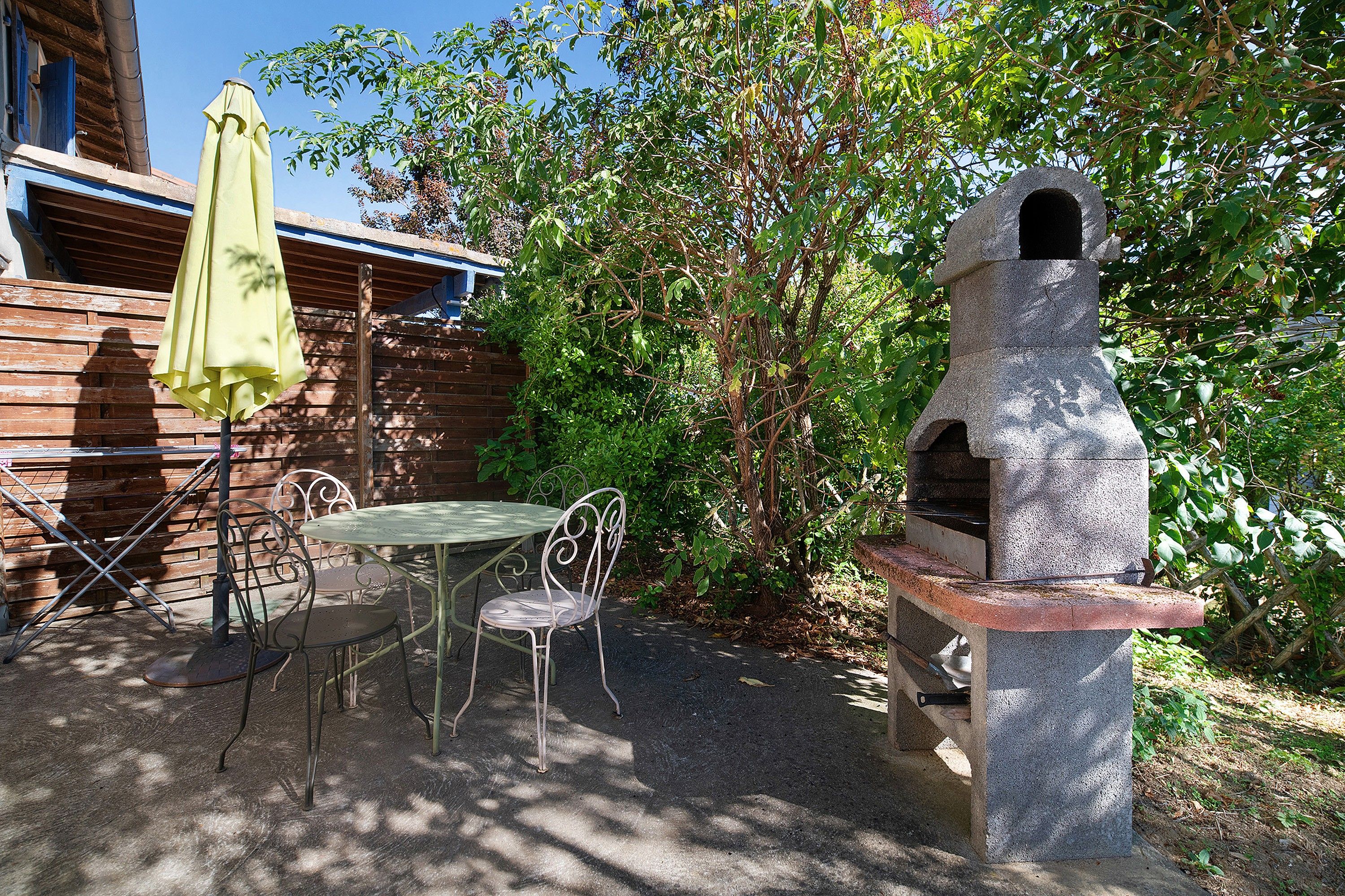 Un espace extérieur aménagé avec un coin salon, un four à pizza en pierre, une table et des chaises.