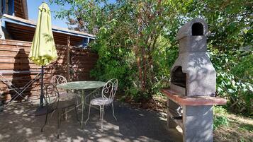 Un espace extérieur aménagé avec un coin salon, un four à pizza en pierre, une table et des chaises.