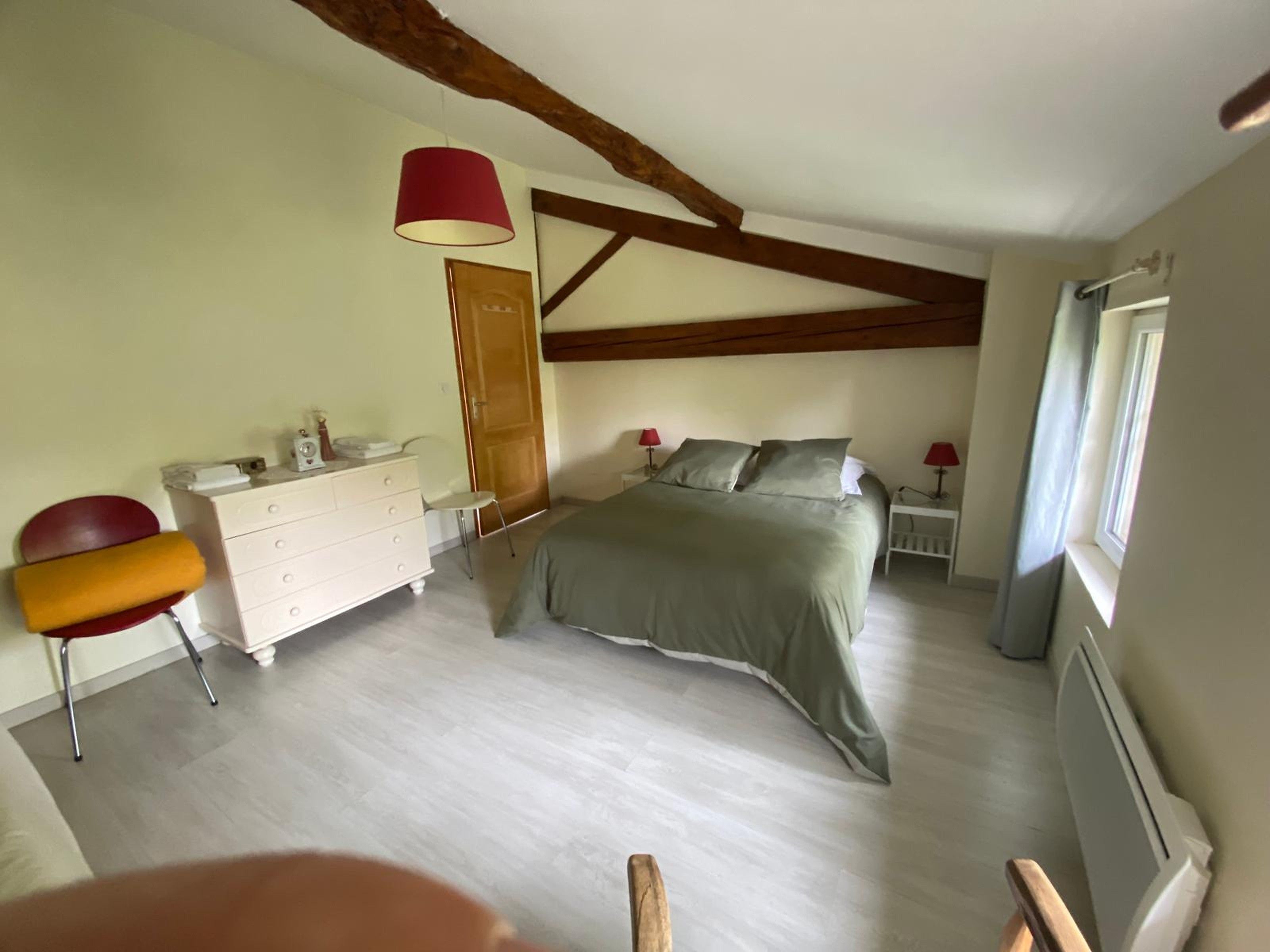 Un dormitorio con cama, cómoda, silla y ventana.