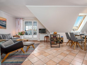 Ein modernes Wohnzimmer mit einer Couch, Sesseln, einem Couchtisch und einem Essbereich mit Stühlen und einem Tisch.