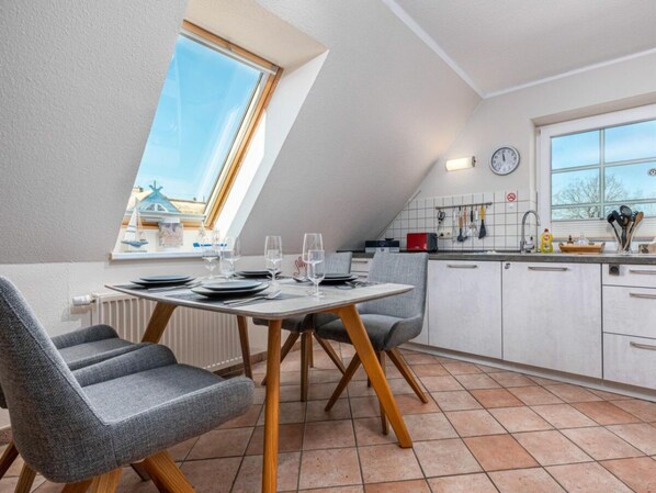 Eine moderne Küche mit Essbereich, inklusive einem für vier Personen gedecktem Tisch, einem Fenster mit Blick und einer Wanduhr.