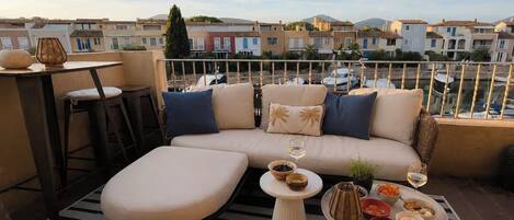 A balcony with a sofa, a small table, and a dining table set with food and drinks.