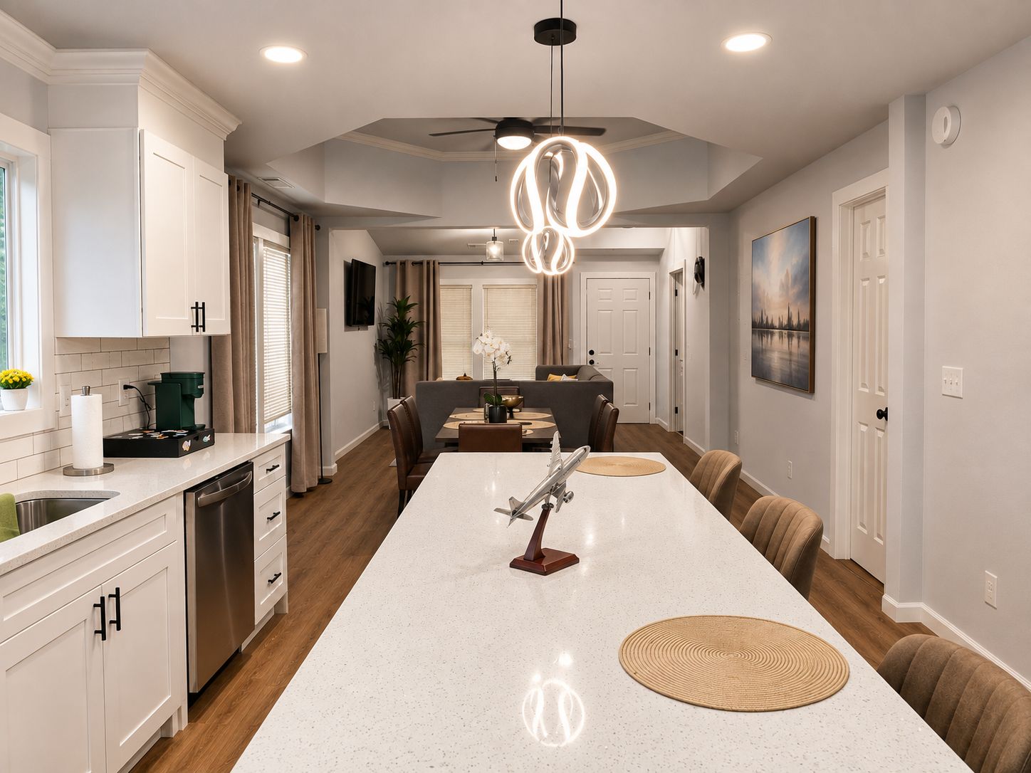 A modern kitchen with a central island, built-in appliances, and a dining area with a sofa and chairs.