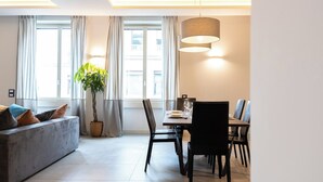 Una sala moderna con sofá, mesa de comedor, sillas y una lámpara colgante.
