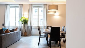 Un soggiorno moderno con divano, tavolo da pranzo, sedie e lampadario.