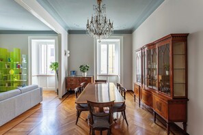 A dining room with a large wooden table, chairs, a chandelier, and a wooden cabinet with glass doors. - Downtown Milan FamilySuite | 6 beds w/ workspace (Milano)