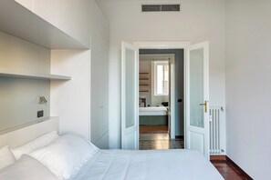 A bedroom with a bed, a wardrobe, a radiator, and a door leading to another room. - Downtown Milan FamilySuite | 6 beds w/ workspace (Milano)