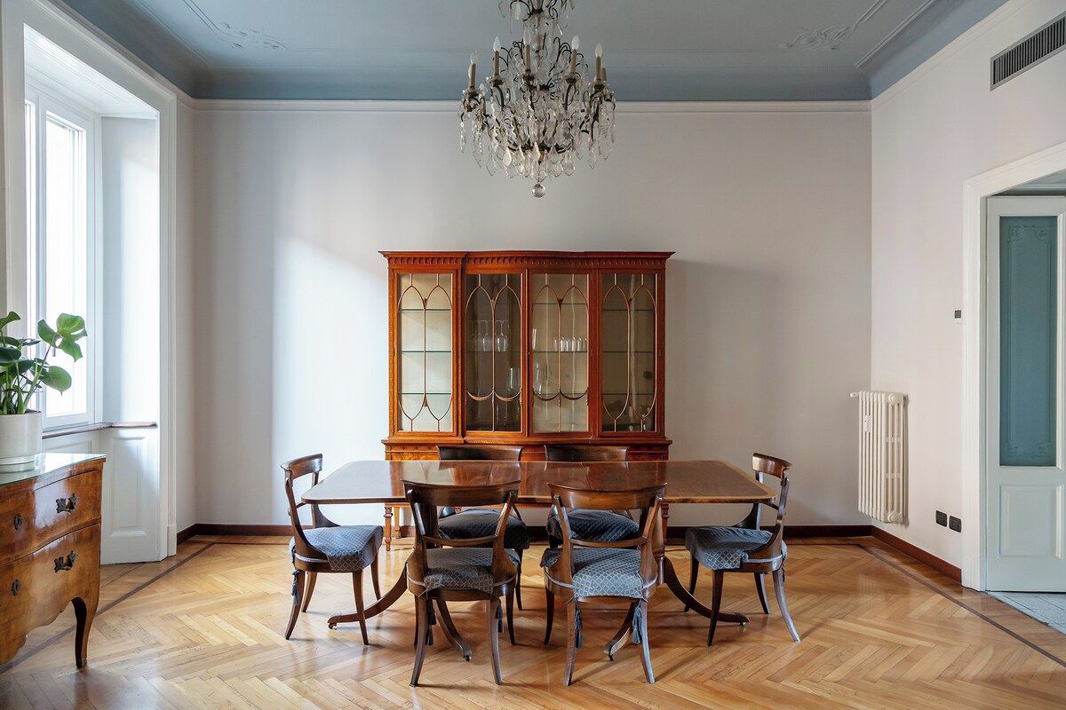 A dining room with a wooden table and chairs, a glass cabinet, and a chandelier.