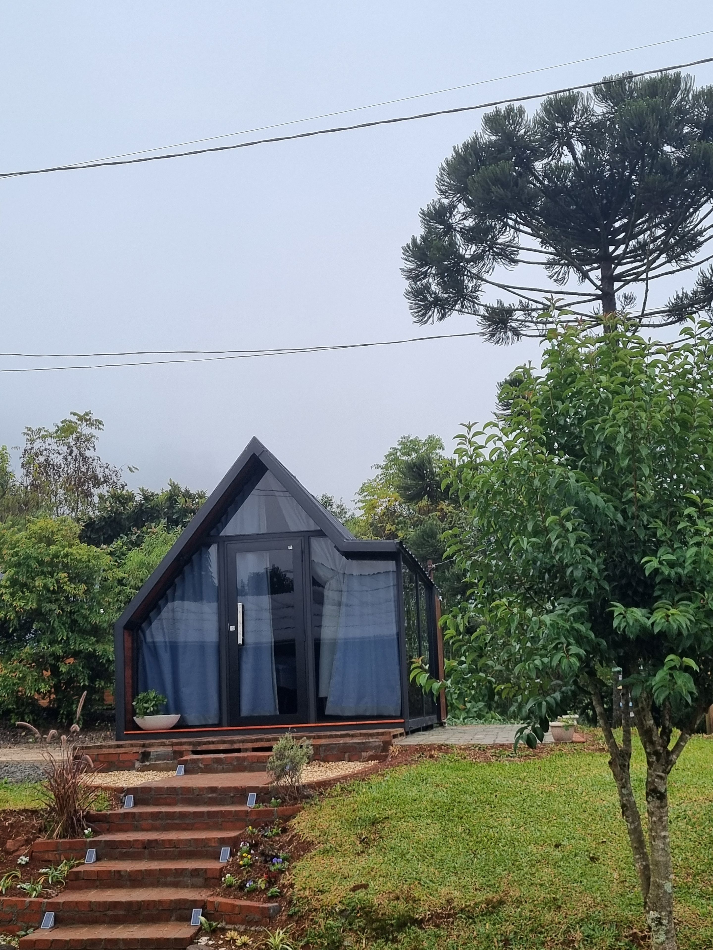 A modern house with a triangular roof, a glass door, and a brick staircase leading to the entrance.