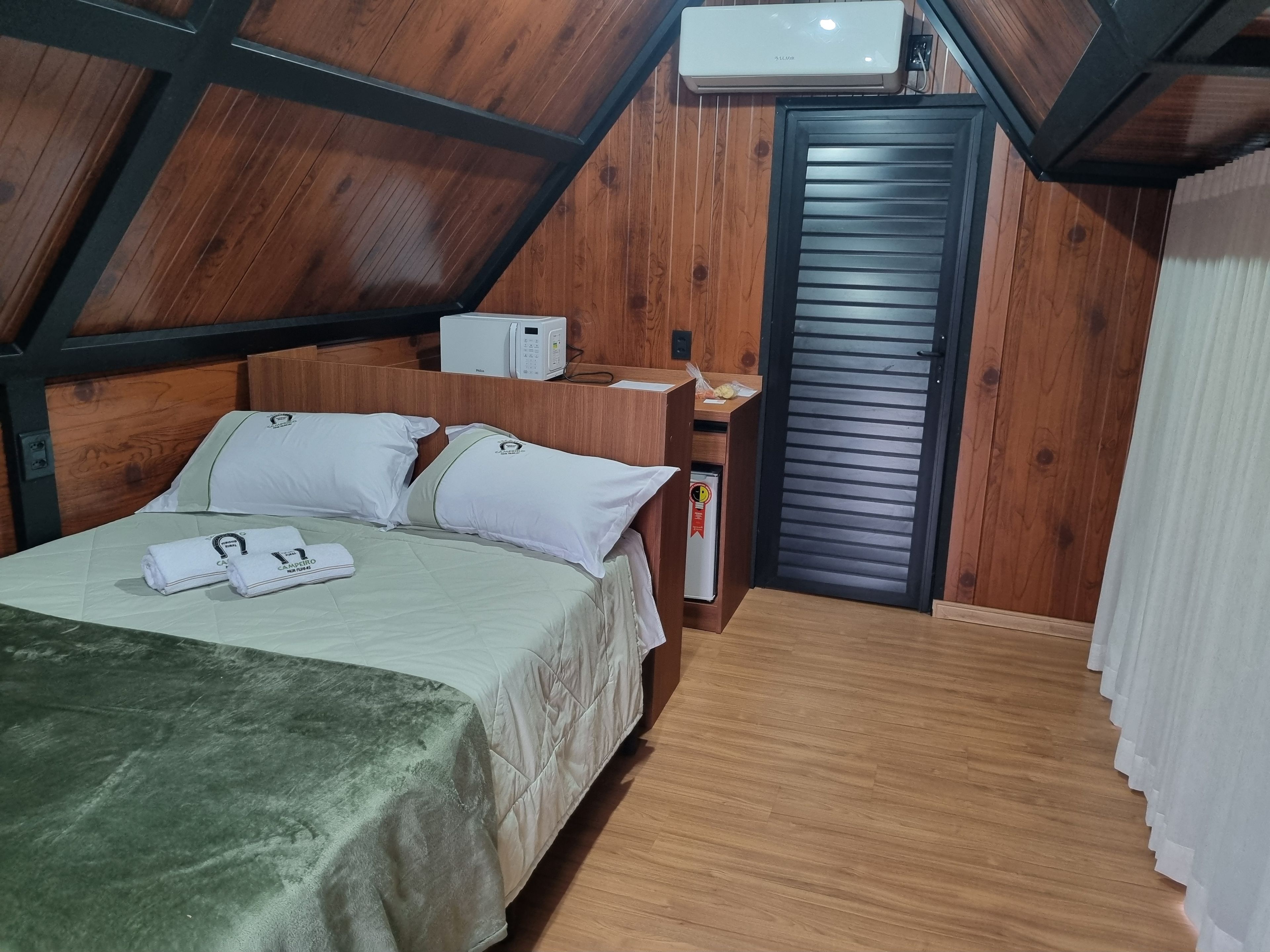 Una habitación con cama, microondas, refrigerador pequeño y una puerta con letrero de seguridad.