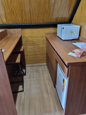 A compact kitchenette with a microwave, a small refrigerator, and a wooden countertop. - Recanto Campeiro (Paim Filho)