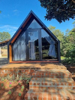 Una casa moderna con techo triangular, amplias ventanas de vidrio y base de ladrillo.
