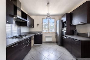Eine moderne Küche mit dunklen Schränken, einem Gasherd, einem Backofen und einem Kühlschrank.