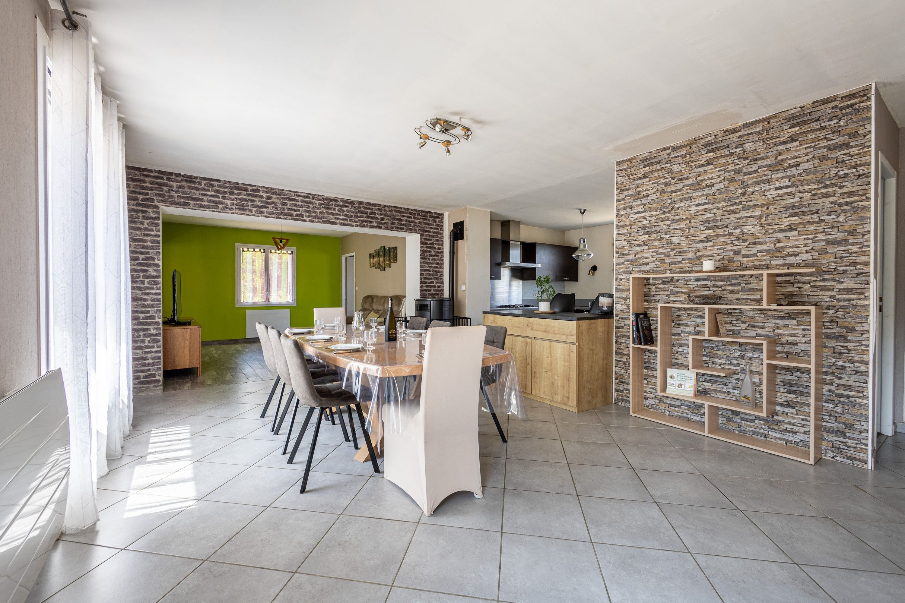 Eine moderne Küche mit Steinrückwand, eine Essecke mit Glastisch und einer leuchtend grünen Akzentwand.