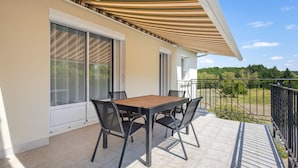 A balcony with a table and chairs, a wooden pergola, and a view of the surrounding landscape. - L’Écrin de Cussac - proche commerces (Cussac)
