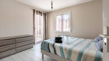 Quarto com cama, penteadeira e janela com cortinas.