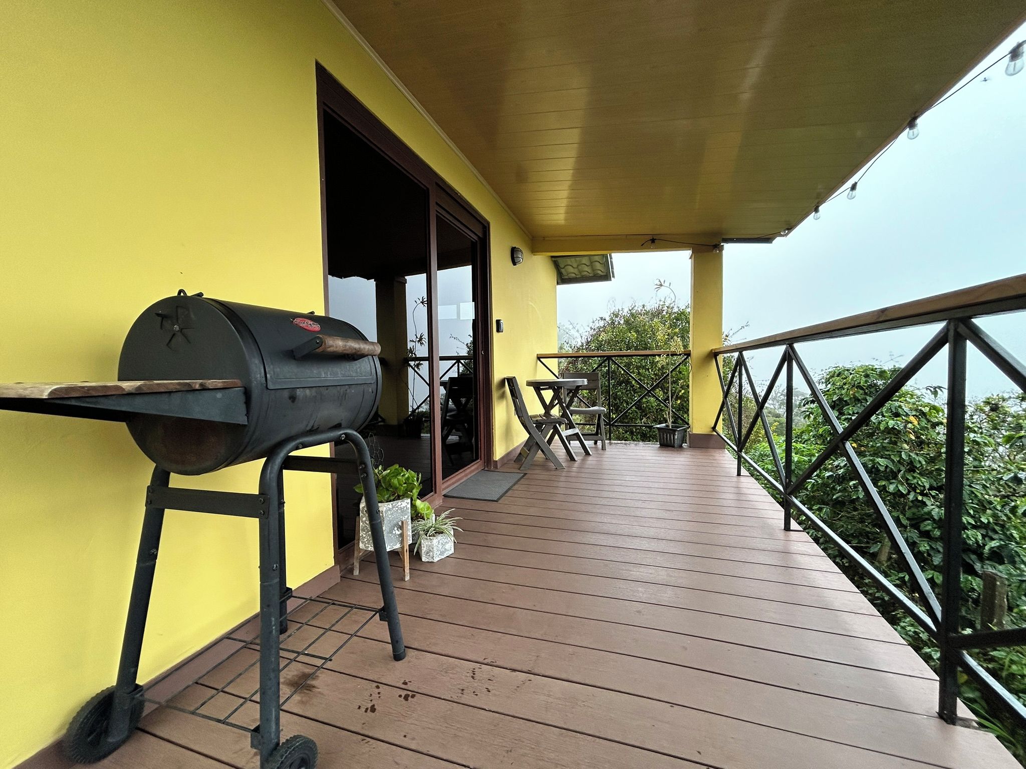 Un patio al aire libre con una parrilla, una mesa y sillas.
