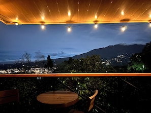 An outdoor seating area with a view of a cityscape and mountains at dusk. - Mountain Cabin with a View of Barú Volcano (Jaramillo)