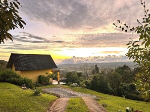 A house with a tiled roof, a paved pathway, and a view of a distant landscape.