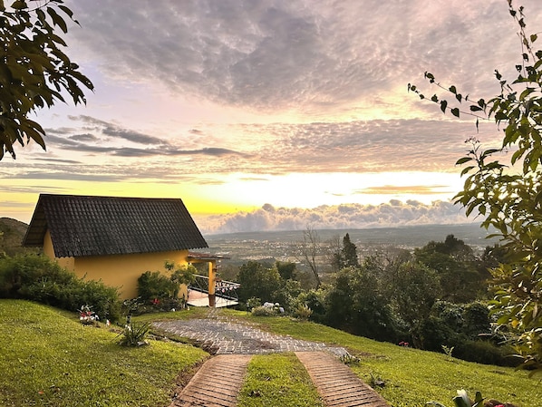 A house with a tiled roof, a paved pathway, and a view of a distant landscape. - Mountain Cabin with a View of Barú Volcano (Jaramillo)