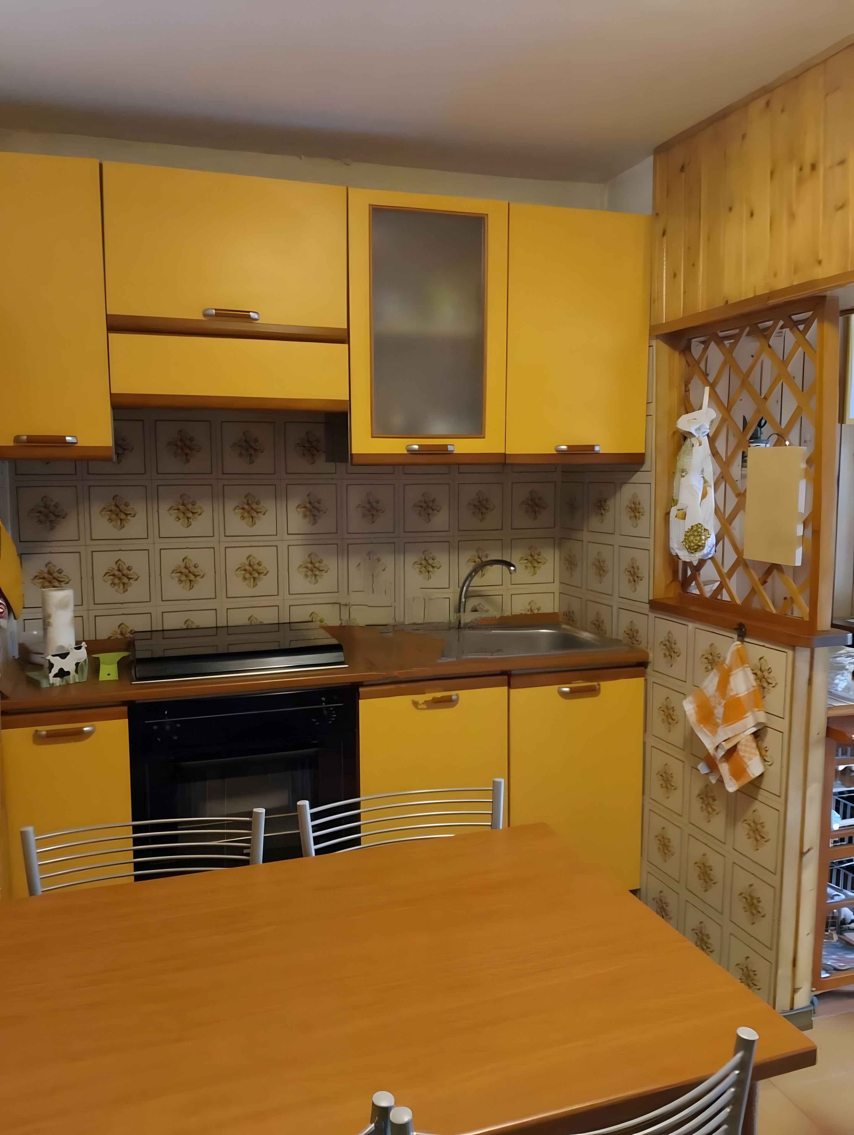 A kitchen with yellow cabinets, a wooden table, and a sink.