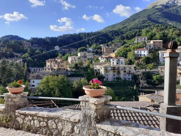 A hillside town with terraced houses, a stone wall, and a metal railing.
