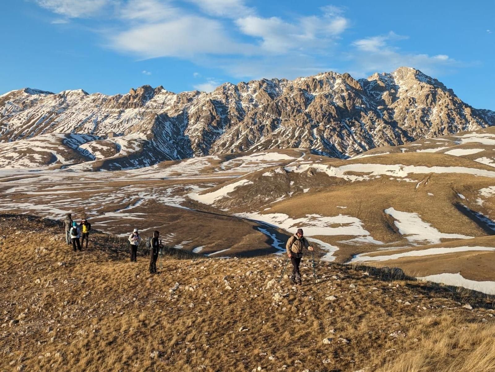 Paisagem montanhosa com caminhantes e céu claro.