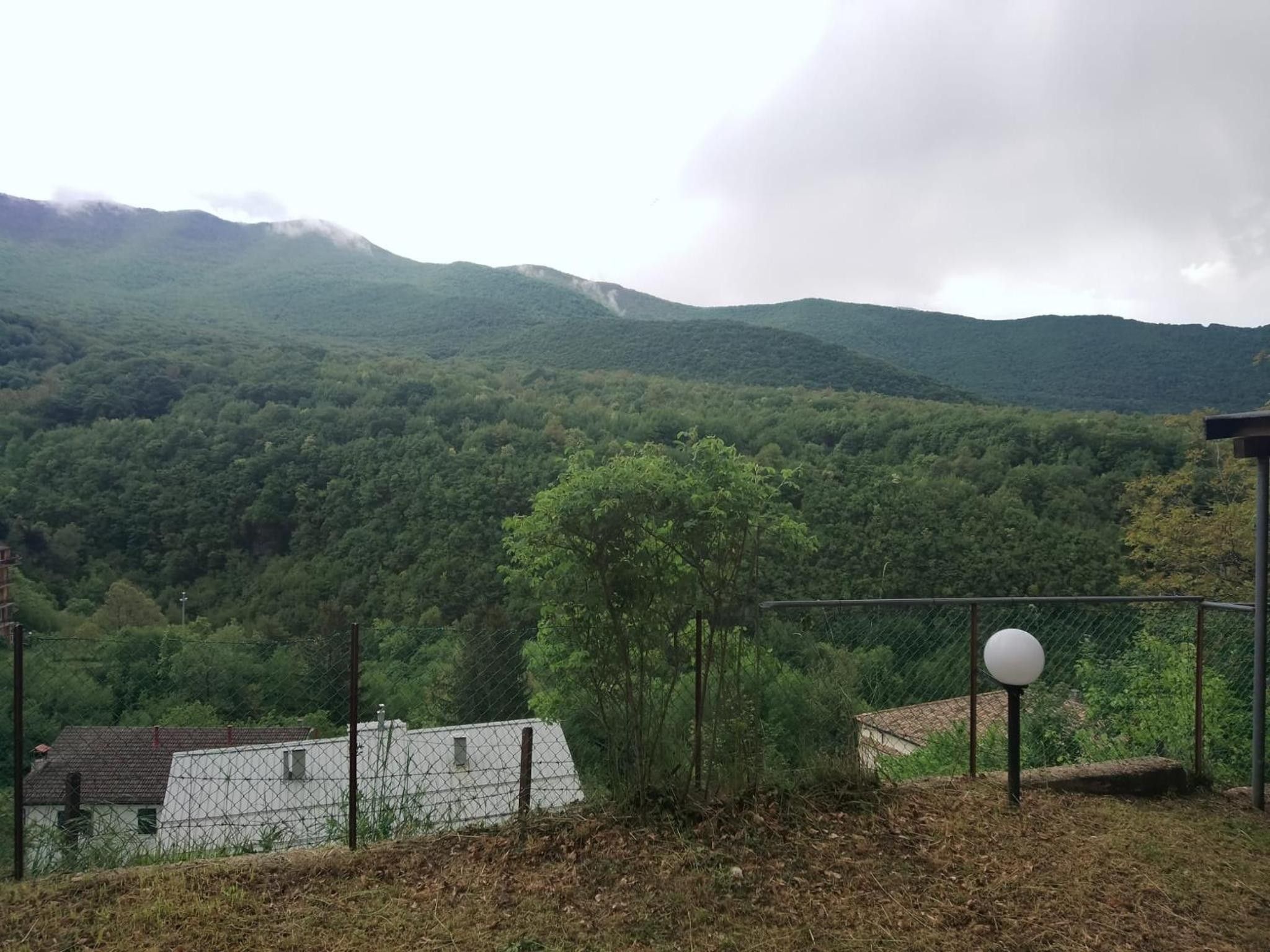 Une propriété clôturée offrant une vue sur une chaîne de montagnes boisée.