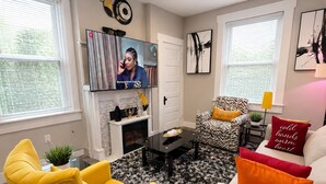 A living room with a yellow armchair, a white sofa, a black and white rug, and a fireplace. - Adorable 2-bedroom apartment with AC in charming Norwood (Norwood)