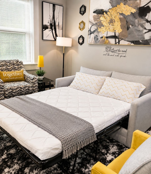 A modern bedroom with a bed, a chair, a bedside table, and a lamp.