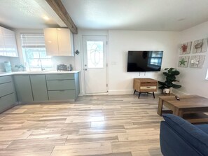 A modern kitchen with a built-in oven, a dining area with a blue sofa, and a flat-screen TV mounted on the wall. -  APARTMENT in Paradise / Cozy 1-Bedroom / Steps to Madeira Beach! (Madeira Beach)