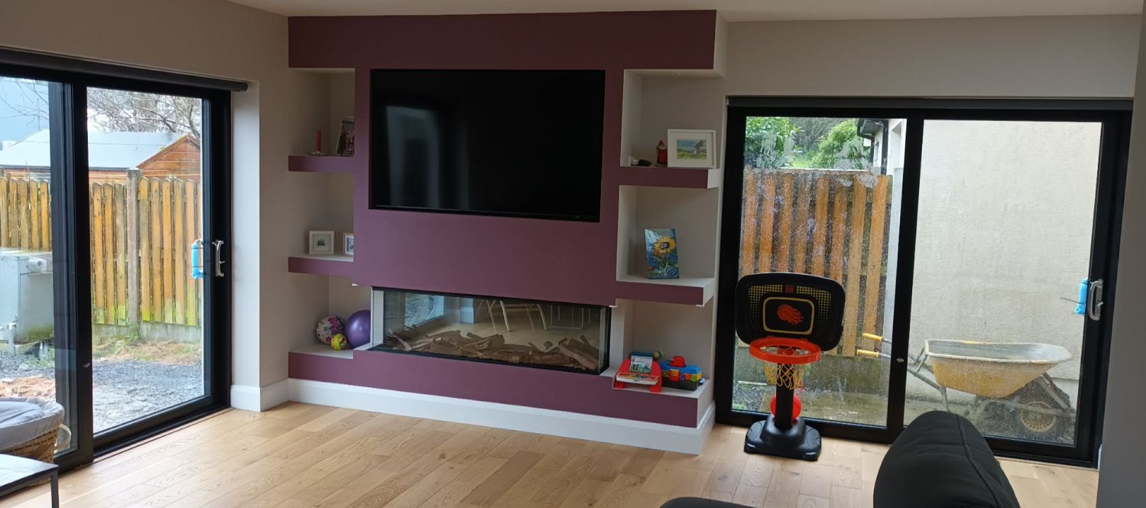 A living room with a fireplace, a television mounted on the wall, and a basketball hoop.