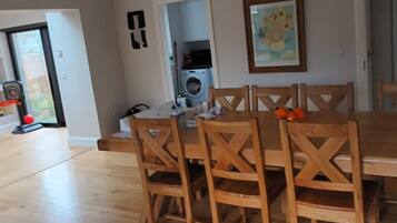 A dining area with a wooden table and chairs, a washing machine, and a door leading to another room.