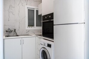 Eine kompakte Küche mit Waschmaschine, Backofen und einem Fenster über der Spüle.