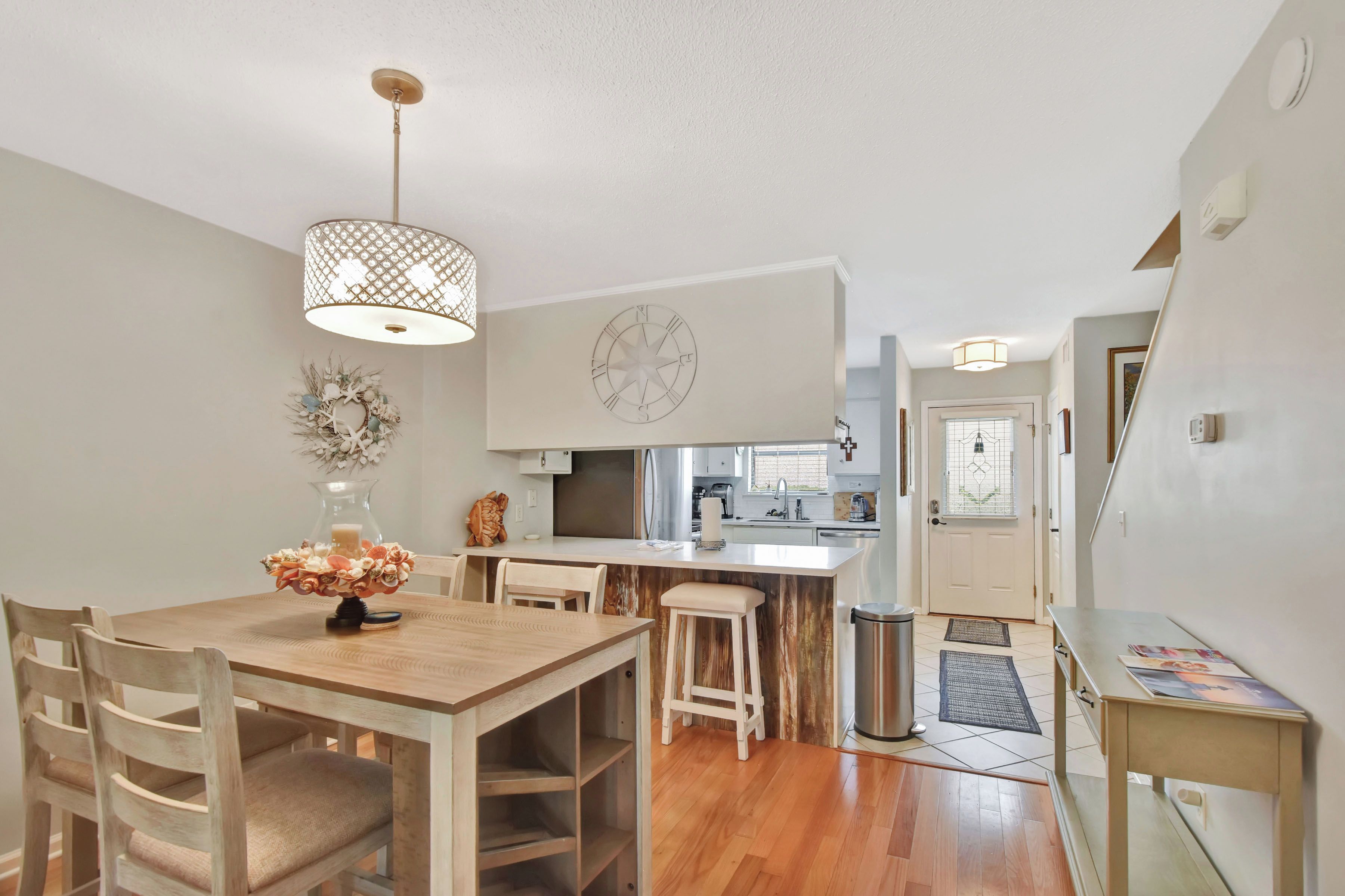 Una cocina moderna con armarios blancos, una mesa de comedor de madera y una lámpara colgante.