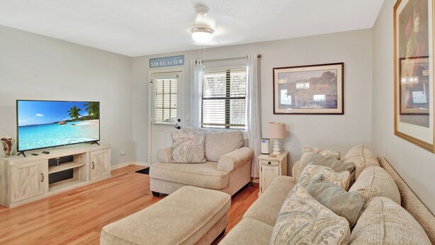 A living room with a flat-screen TV, a sofa set, a coffee table, and a side table with a lamp. - Great condo 1/2 mile to the pier village and 3/4 mile to the beach (Saint Simons Island)