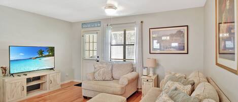 A living room with a flat-screen TV, a sofa set, a coffee table, and a side table with a lamp.