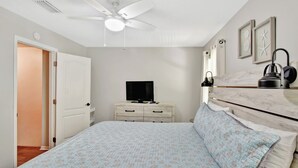 A bedroom with a bed, a ceiling fan, a dresser, a television, and a nightstand. - Great condo 1/2 mile to the pier village and 3/4 mile to the beach (Saint Simons Island)