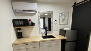 Eine kleine Küche mit Mikrowelle, Kaffeemaschine und Kühlschrank.