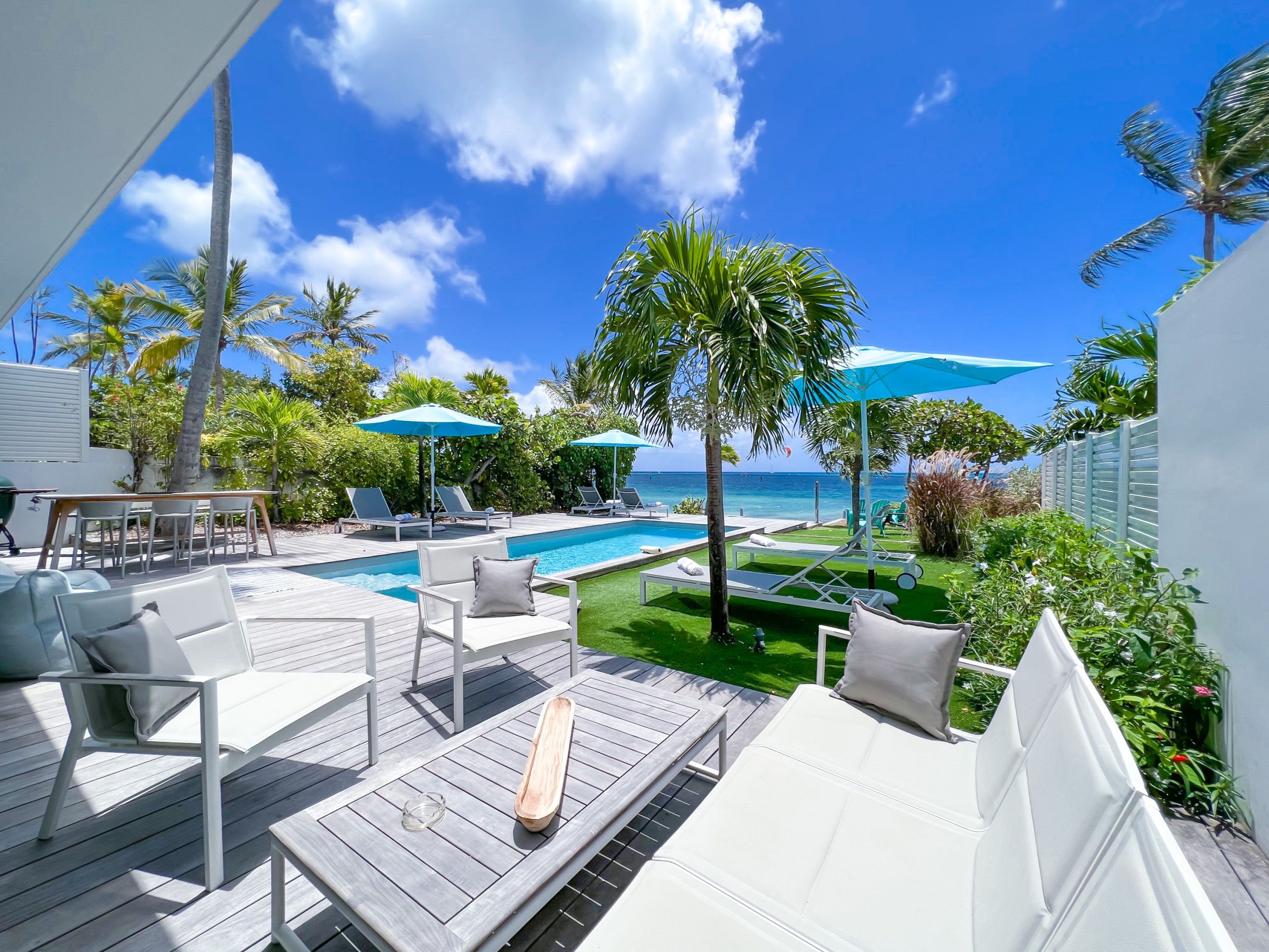 A poolside area with lounge chairs, umbrellas, and a view of the ocean.
