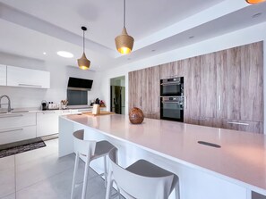 A modern kitchen with a large island, built-in ovens, and pendant lighting. - Luxury villa · St-François · Sea view & beach access (Saint-François)