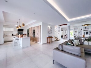 A modern open-plan living area with a kitchen, dining space, and a staircase leading to another level. - Luxury villa · St-François · Sea view & beach access (Saint-François)